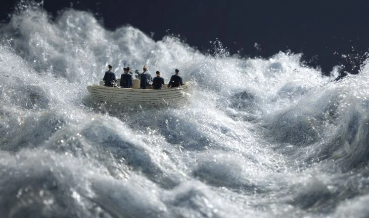 a small boat with plastic men in a sea of cotton wool