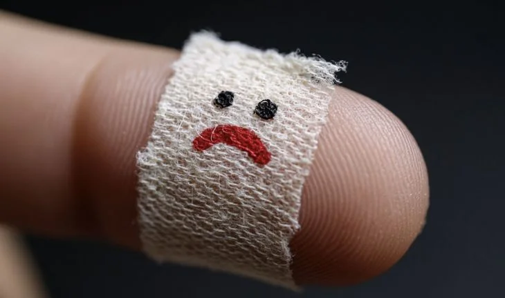 a finger with a bandage with a sad face