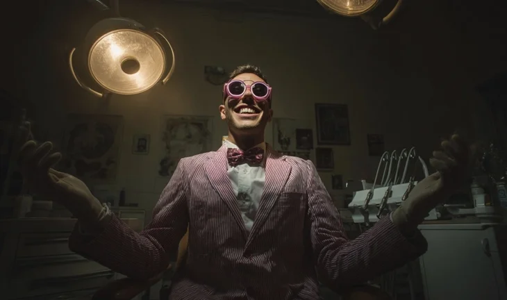 a man in a stripy suit under overhead lights wearing pink gloves