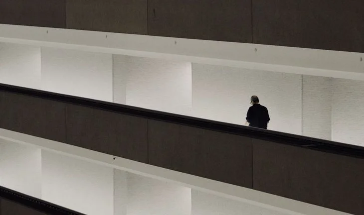a man walking along dark walkways in a white building 