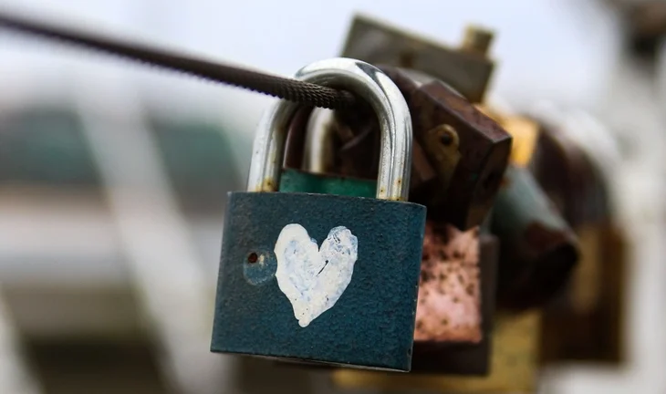 a padlock on a bridge. there is a white loveheart, maybe it's tippex